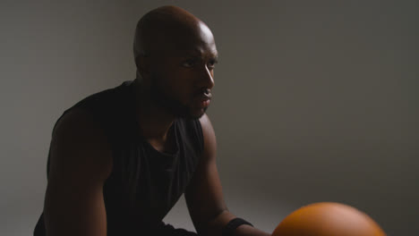 Studio-Shot-Of-Seated-Male-Basketball-Player-With-Hands-Holding-Ball-3